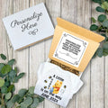 Baby shower gift set with personalized message card and Winnie the Pooh-themed blanket on a wooden surface.