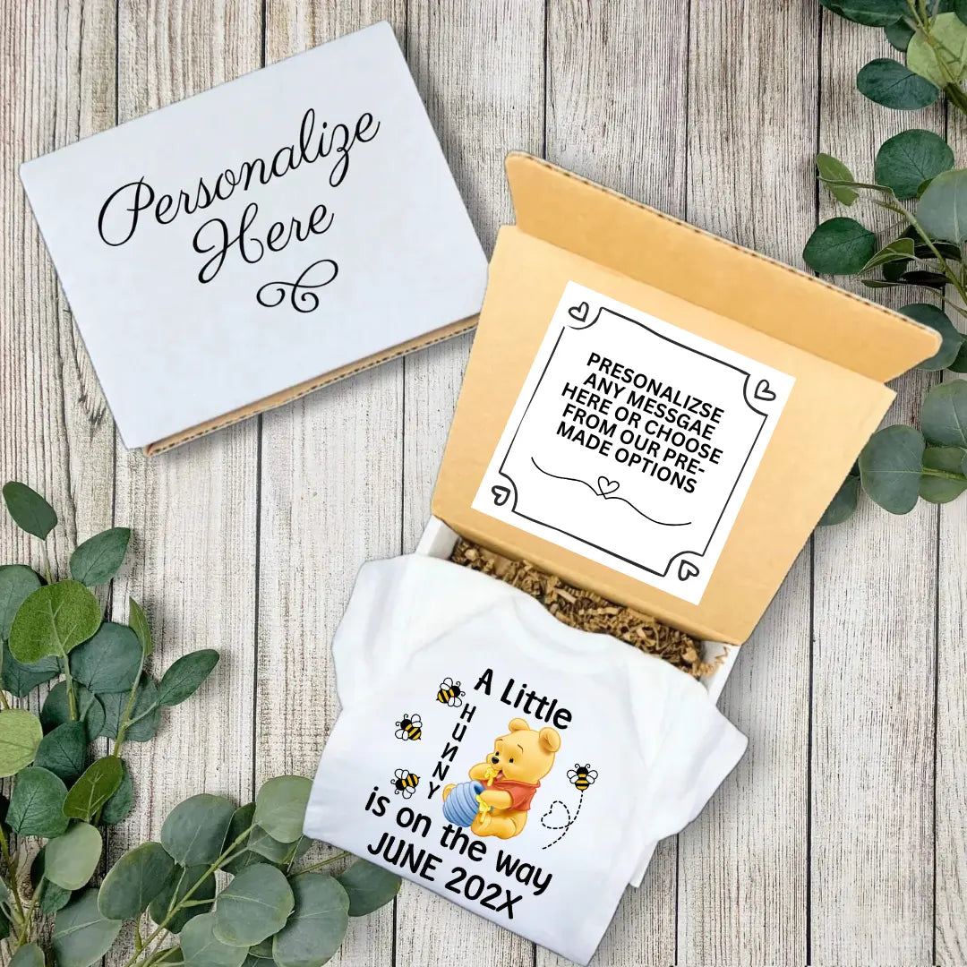 Baby shower gift set with personalized message card and Winnie the Pooh-themed blanket on a wooden surface.