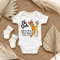 Baby onesie with 'Oh Deer We're Due This Year! June 202x' text and Bambi graphic on a textured surface.
