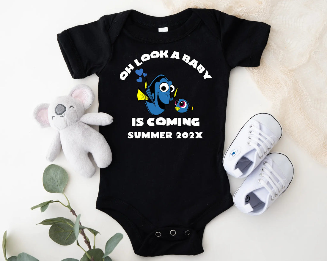 Baby onesie with Dory and Nemo design, baby shoes, and plush toy on a light background
