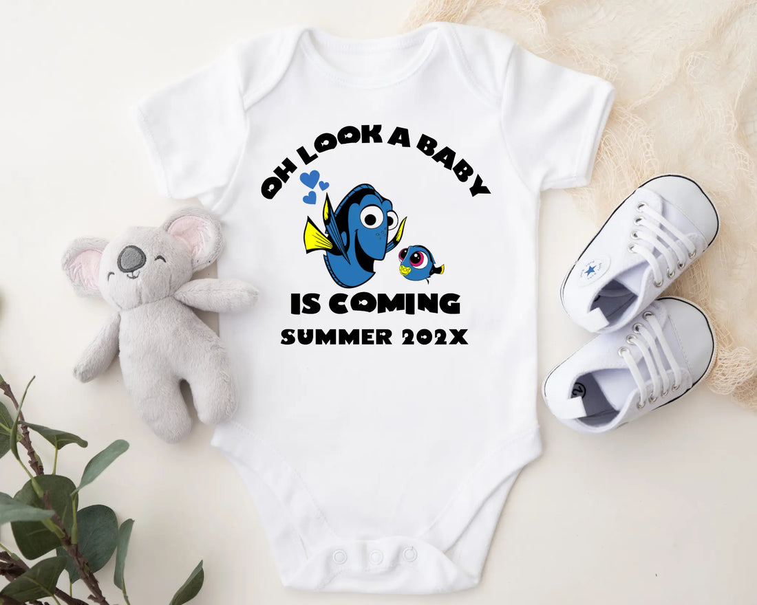 Baby onesie with Dory and Nemo design, baby shoes, and plush toy on a light background