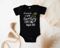 Black baby onesie with text and turtle graphic on a light background