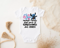 White baby onesie with cartoon character and text on a textured surface